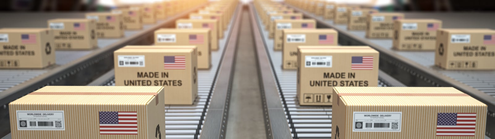 Photo of cardboard boxes moving down a conveyor belt. Each box is stamped with the words "Made in America." There are several American flags hanging in the background.