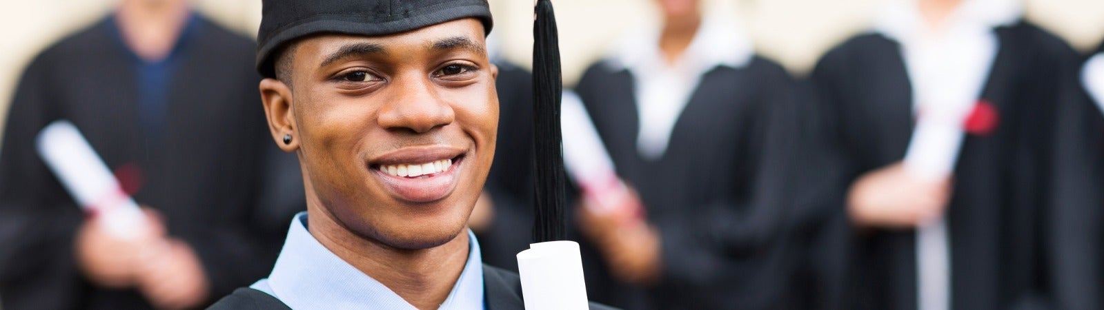 Student in graduation cap and gown, holding a diploma