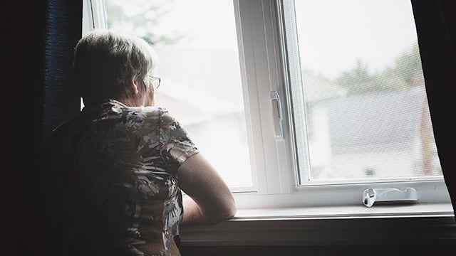 Senior woman looks out window