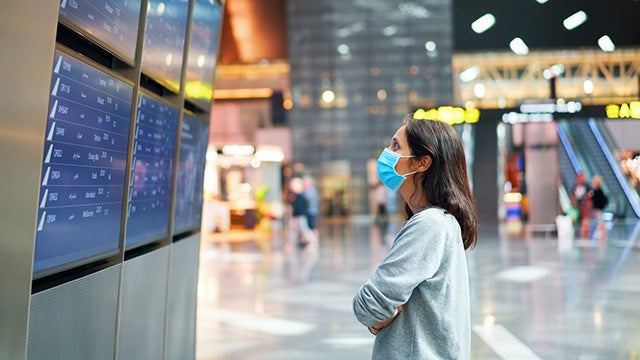 Woman with mask looking at departure board